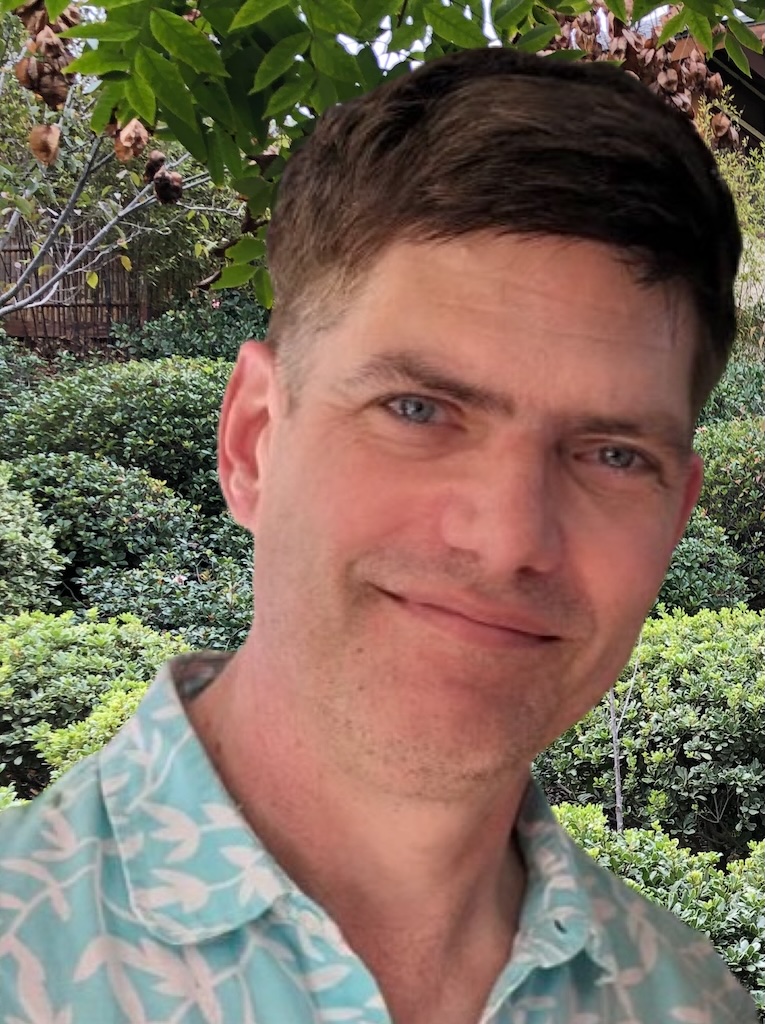 Dale Decker, LCSW smiles into the camera. He is standing in a garden.